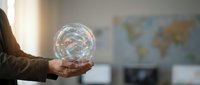 Professional businessman holding glowing transparent globe with network connections in modern office environment for global business concepts.