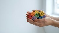 Hands holding colorful wooden blocks with emoji faces showing different emotions for mental health awareness and emotional wellbeing concepts.