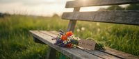 Wildflower bouquet with be kind tag resting on rustic wooden bench in sunny meadow, soft golden light, kindness and nature concept.