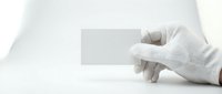 Hands in white gloves holding blank white card on isolated white background, ready for design mockups, branding presentations, and promotional materials.