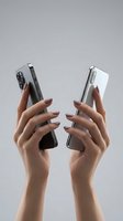 Female hands holding two modern smartphones with manicured nails against neutral background for technology and communication concepts.