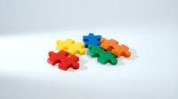 Colorful interlocking puzzle pieces in red, yellow, blue, green, and orange arranged on white surface, representing teamwork, problem-solving, and business solutions.