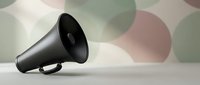 Black megaphone on a light surface with a soft geometric circle pattern background, symbolizing communication, announcement, and public speaking.