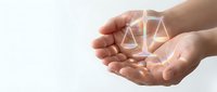 Hands holding glowing scales of justice symbol, representing law, legal services, fairness, and compliance for business and corporate design projects.