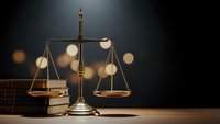 Golden brass scales of justice on wooden desk with law books in atmospheric lighting for legal and judicial concepts.