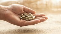 Close-up of open palm holding nutritional supplement capsules, depicting wellness, healthcare, and dietary supplement consumption for medical and health-related design projects.