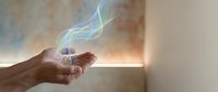 Hands cupped holding glowing blue energy waves with magical light effects in warm indoor setting for spiritual healing and wellness concepts.