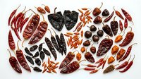 Assorted dried chili peppers collection featuring various shapes, sizes and heat levels arranged on white background for culinary spice cooking ingredients.
