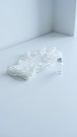 Clear disposable gloves and glass vial on white surface in minimalist medical laboratory setting for healthcare and scientific research applications.