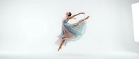 Young female ballet dancer in graceful leap wearing flowing pastel tutu against white studio background. Ideal for dance, performance, and artistic projects.