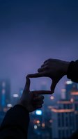 Hands forming frame gesture against blurred city lights at dusk for creative vision and planning concepts.