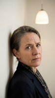 Mature Caucasian businesswoman in dark suit looking serious and contemplative in modern office setting with pendant lighting for corporate communications.