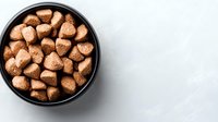 Cinnamon sugar coated cereal pieces in black bowl on white wooden background. Crunchy breakfast food for morning meal.