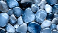 Polished blue and gray stones background with smooth rounded pebbles in cool tones creating tranquil zen pattern for spa and wellness design.