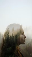 Young woman with long reddish-brown hair in profile, forest landscape double exposure with misty evergreen trees and fog blended into her silhouette for nature and wellness concepts.