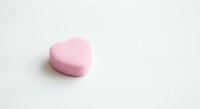 Pink heart-shaped candy on white background for Valentine's Day romance love sweet treat dessert confectionery holiday celebration gift present.