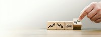 Business growth concept with hand arranging wooden blocks showing upward trending charts and graphs on neutral background for financial success presentations.
