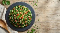 Fresh tabbouleh salad with parsley, tomatoes and bulgur on slate plate, healthy Mediterranean cuisine on rustic wooden background for cooking blogs.