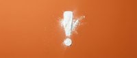 White chalk exclamation mark with dust particles on vibrant orange background for attention-grabbing designs and educational materials.
