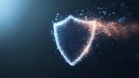 Shield symbol made of glowing particles dispersing into digital dust against dark blue background, representing cybersecurity, data protection, and network defense technology.