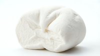 Fresh white mozzarella cheese ball torn in half showing creamy texture isolated on white background for culinary and food photography projects.