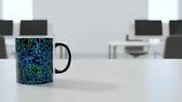 Circuit board pattern coffee mug on modern office desk with computers in background. Technology workplace concept for IT professionals and engineers.