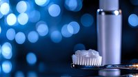 Toothbrush with toothpaste and metallic bottle against blurred blue bokeh lights, suitable for dental care, hygiene, and wellness product marketing.