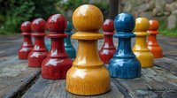 Colorful wooden chess pawns arranged in line with focus on orange and blue pieces, showing leadership and strategy concept on rustic wooden surface.
