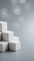 White rounded cubes stacked in a staircase formation on a gray surface with soft bokeh background, symbolizing growth and structure.