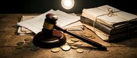 Wooden gavel with legal documents and coins on rustic desk under warm lighting for law office, legal services, justice system concepts.
