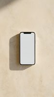 Smartphone with blank white screen on beige textured surface, casting shadow. Mockup for app design, website display, or mobile marketing campaigns.