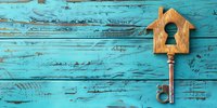 Vintage house shaped key on turquoise blue weathered wooden background with copy space. Real estate, mortgage and home security concept.