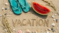 Vacation word written in sand surrounded by seashells, teal flip flops, and fresh watermelon slice on sunny beach, summer holiday concept.