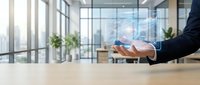 Businessman holding holographic digital interface in modern office with city skyline view through glass windows for technology and innovation concepts.