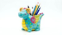 Colorful decorative dinosaur figurine holding pencils and art supplies, isolated on white background for creative design projects and educational materials.