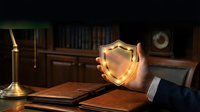 Golden shield emblem glowing in businessman hands at wooden desk with law books and candle creating professional legal protection concept.