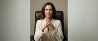 Professional businesswoman in white suit sitting confidently in executive chair with hands clasped, corporate leadership and success concept.