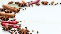 Aromatic spices and herbs arranged on white background with copy space for culinary designs, cooking recipes, and food preparation concepts.