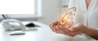 Hands holding glowing crystal with golden light particles, representing innovation, technology, and digital transformation in modern business environment.