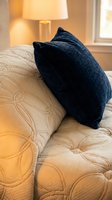 Dark blue textured throw pillow resting on cream quilted bedding in warm lamplight, showcasing home decor and bedroom styling for interior design projects.