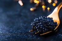 Black caviar on golden spoon against dark background with bokeh lights, luxury gourmet food close-up macro photography for restaurant menu and fine dining.