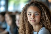 Young African American woman with natural curly hair smiling confidently in office environment, wearing casual business attire against blurred background.