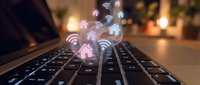 Digital connectivity concept with glowing WiFi and home automation icons floating above laptop keyboard in warm cozy interior setting for smart technology.
