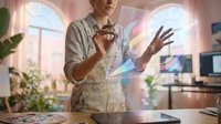 Young Caucasian female artist interacts with a holographic digital interface in a creative studio, blending art and futuristic technology.