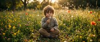 Toddler with curly blonde hair sitting in wildflower meadow at golden hour, holding dandelion, wearing brown shirt, surrounded by green grass and red poppies.