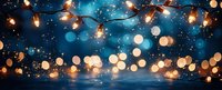 Festive string lights with warm golden glow against dark blue bokeh background creating magical holiday atmosphere.
