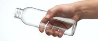 Person with medium skin tone pouring water from empty glass bottle, isolated on white background for beverage, hydration, recycling and sustainability concepts.
