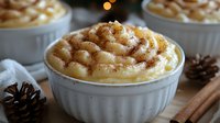Creamy mac and cheese topped with golden breadcrumbs in white ceramic ramekin, with pine cones and cinnamon sticks creating cozy winter atmosphere.