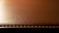 Brown leather surface with decorative stitching detail showcasing craftsmanship and texture for luxury goods and fashion accessories design projects.