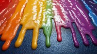 Vibrant rainbow colored paint drips flowing downward on dark textured surface, creating dramatic contrast with glossy wet appearance and rich saturated hues.